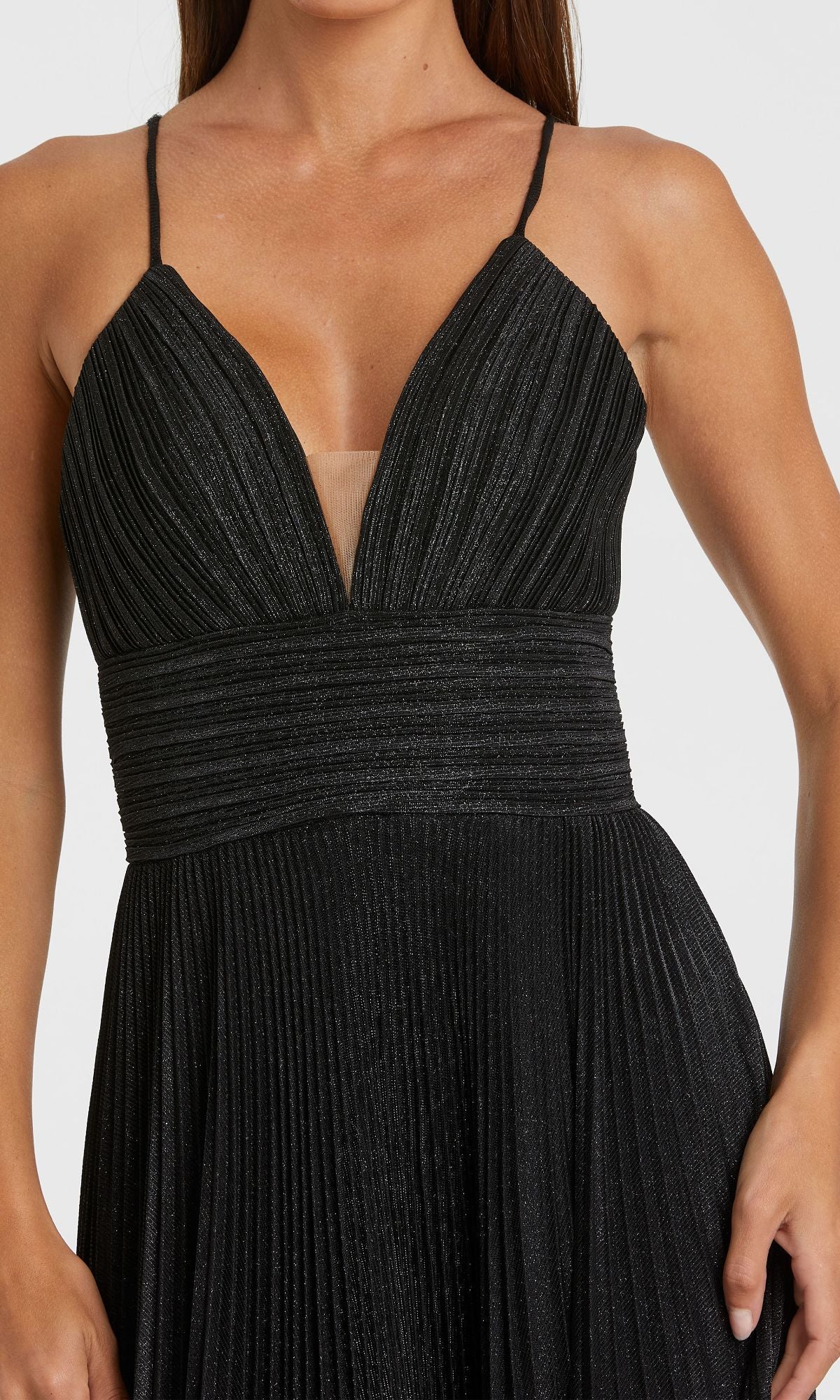 A woman wears the Pleated Empire-Waist Long A-Line Prom Dress 30725, a sleeveless black gown with a deep V-neckline, fitted waist, and elegant pleats—perfect for a chic prom look.